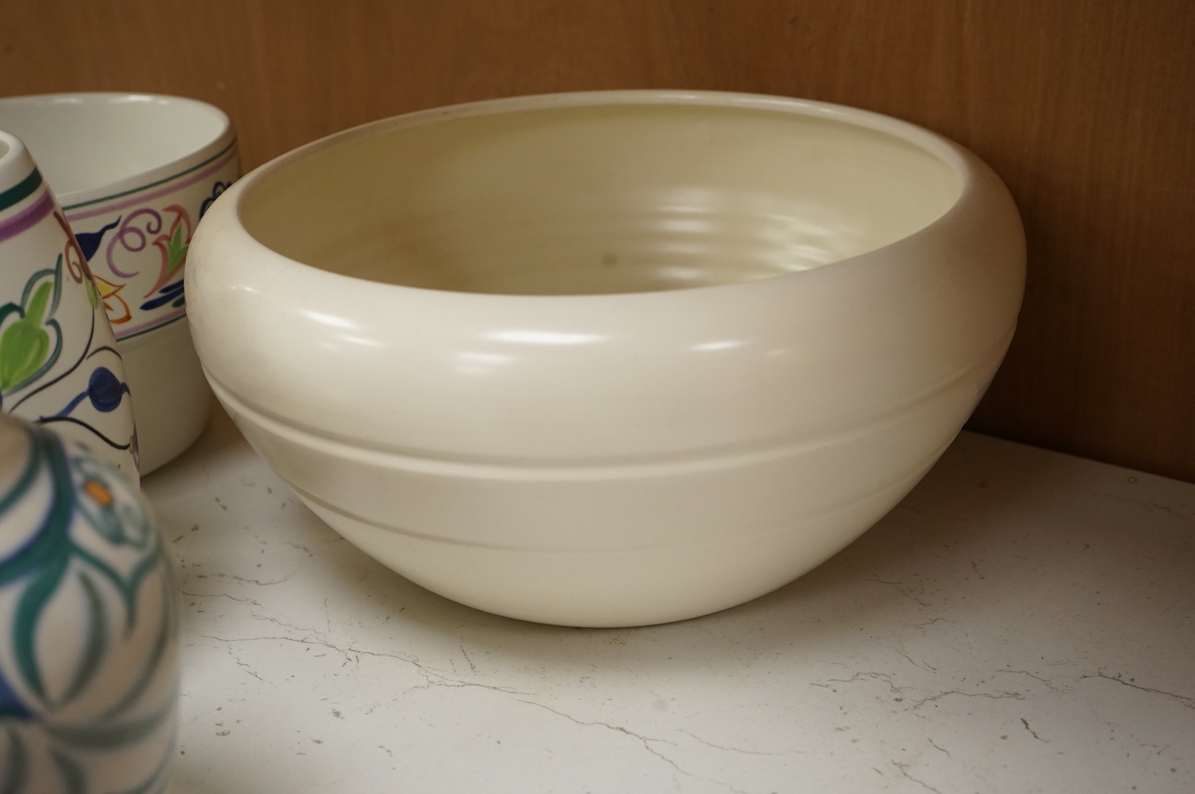 A collection of eight Poole pottery pieces to include vases, bowls and a jar and cover, largest 28cm in diameter